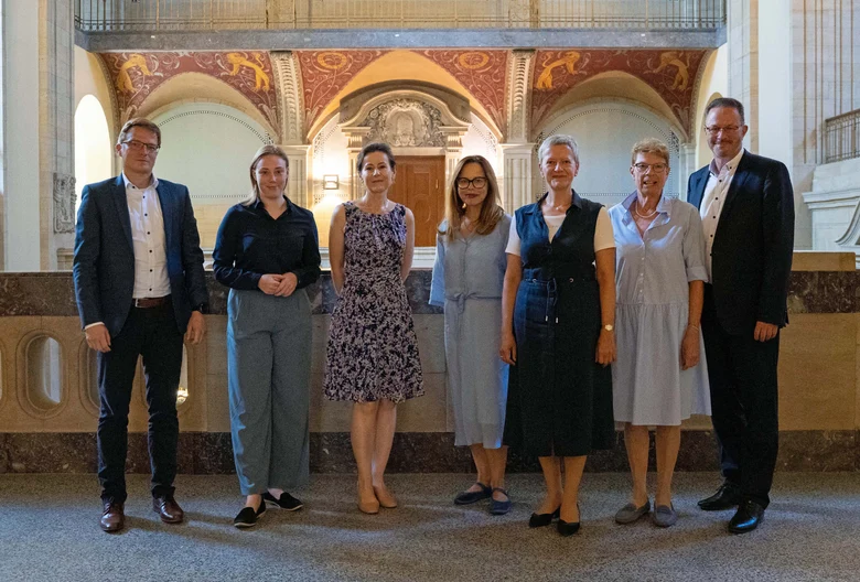 Männer und Frauen stehen in einer Halle nebeneinander.