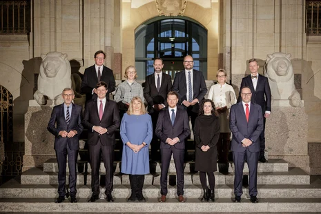 Mehrere Menschen posieren auf einer Treppe für ein Gruppenfoto.