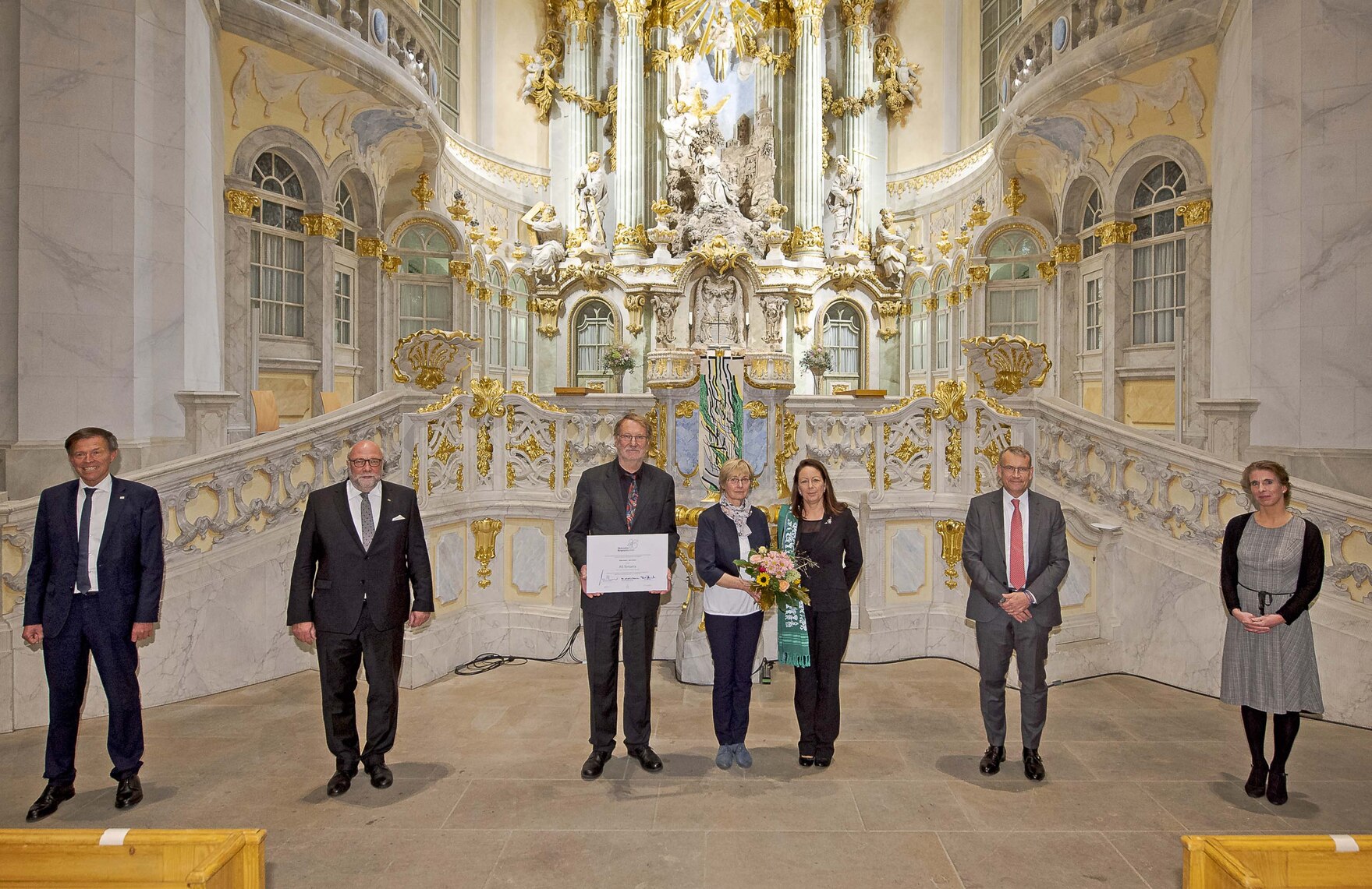 Männer und Frauen stehen vor dem Altar der Dresnder Frauenkirche.