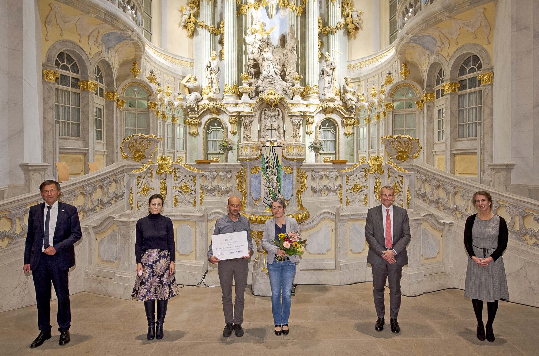 Männer und Frauen stehen vor dem Altar der Dresdner Frauenkirche.