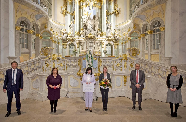Männer und Frauen stehen vor dem Altar der Frauenkirche in Dresden.