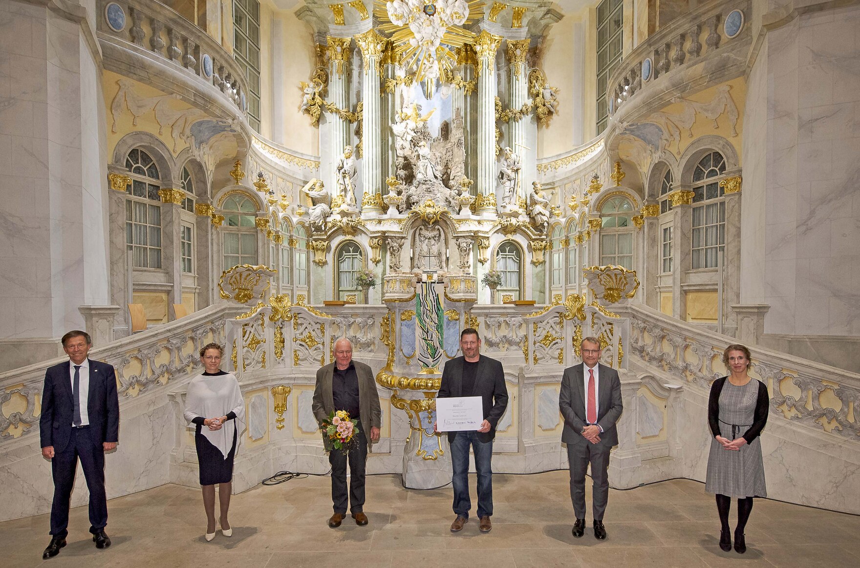 Männer und Frauen stehen vor dem Altar der Dresdner Frauenkirche.