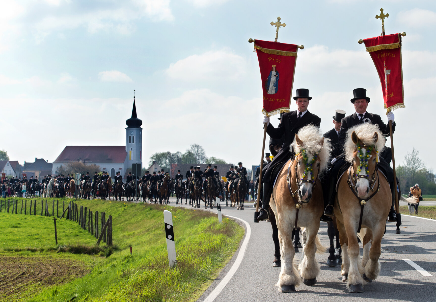 Osterreiterpaar führt mit christlichen Bannern eine lange Osterreiterprozession über die sorbischen Dörfer an.